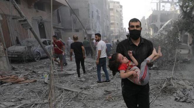 فلسطيني يحمل طفلة