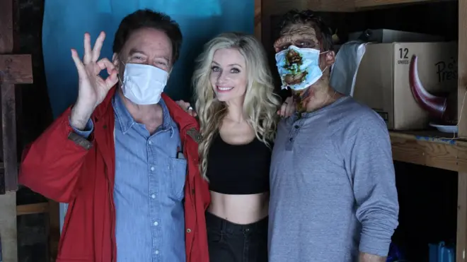 Редитељ Чарлс Бенд (лево) са глумицом Коди Рене Камерон (средина) и зомбијем зараженим корона вирусом.