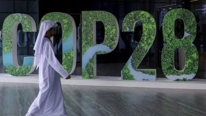Man walking in front of COP28 sign