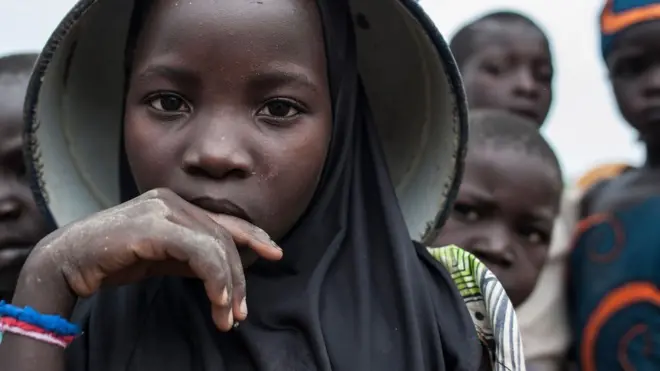 African female pikin wey carry pan for head.