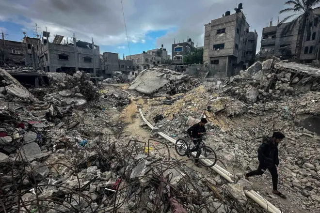 Palestyńczycy idą wśród gruzów, oglądając domy zniszczone w izraelskich atakach podczas konfliktu, w czasie tymczasowego rozejmu między Hamasem a Izraelem, w obozie dla uchodźców Chan Junus w południowej Strefie Gazy