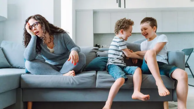 طفلان يلهوان إلى جوار امرأة شابة