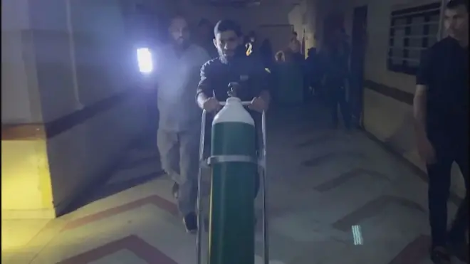 أحد أفراد طاقم التمريض في مستشفى الشفاء يحمل أسطوانة أكسجين