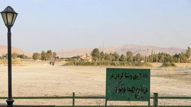 تابلوی «شنا ممنوع» جلوی دریاچه سرآب نیلوفر که خشک شده است. 