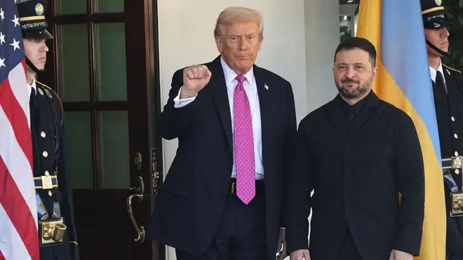 ډونلډ ټرمپ له زيلېنسکي سره ولاړ دی او ښی لاس یې موټی او اوچت کړی دی.