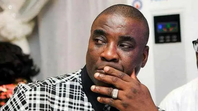 Aworan Wasiu Ayinde, to fi ọwọ to fi oruka si bo ẹnu ninu aṣọ funfun ati dudu