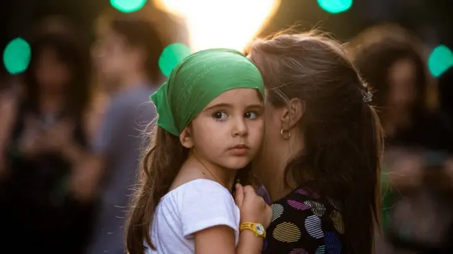 Una niña cargada por su madre.