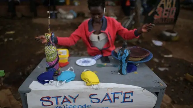 امرأة تبيع أقنعة وجه مصنوعة من القماش في حي كيبيرا، نيروبي - قامت كينيا حتى الآن بتطويق العاصمة وأجزاء من سواحلها وفرضت حظر التجول ليلا في محاولة للحد من انتشار فيروس كورونا.