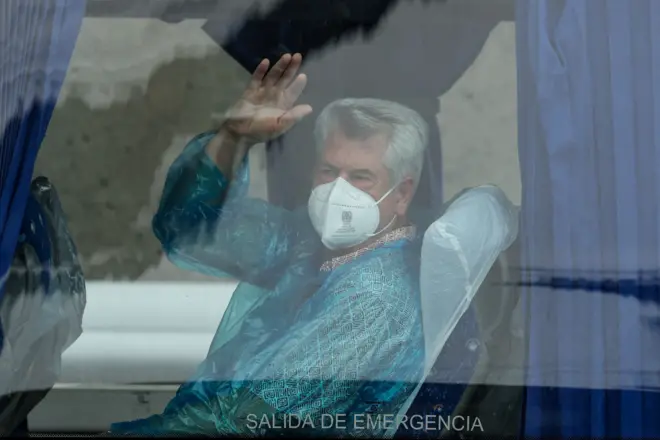 Stariji muškarac maše iz autobusa, ima masku na licu i u zaštitnom je odelu