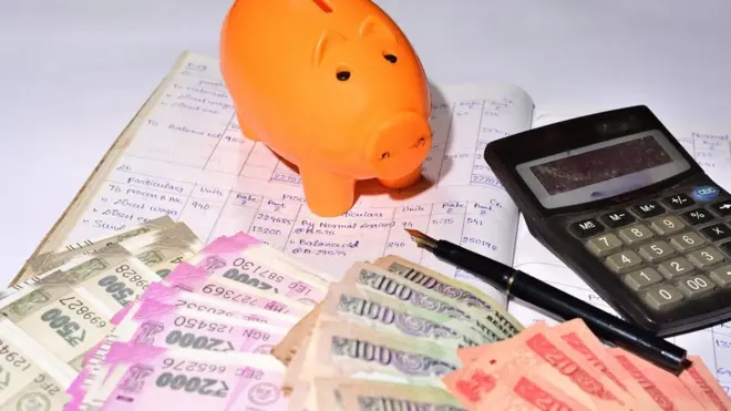 રૂપિયાની નોટો સાથે કેલ્ક્યુલેટર અને હિસાબબુક