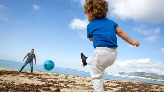 A child plays football with his father at Can Pere Antoni Beach in Palma de Mallorca, on 26 April 2020