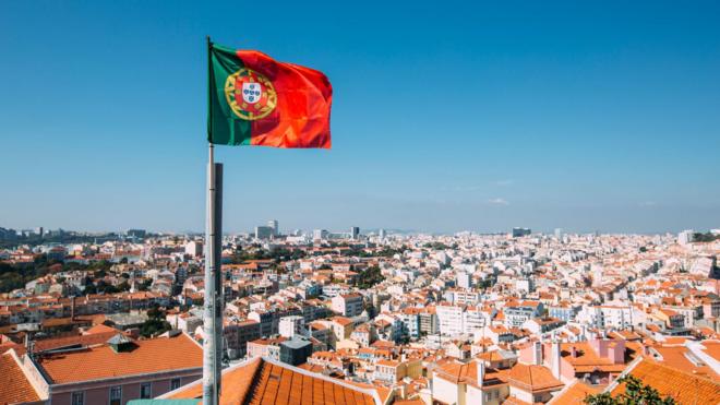 bandeira de Portugal com Lisboa ao fundo 