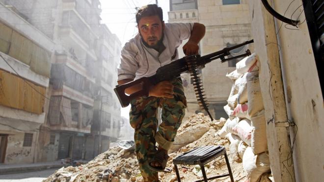 Un hombre armado corre en una destruida Alepo.