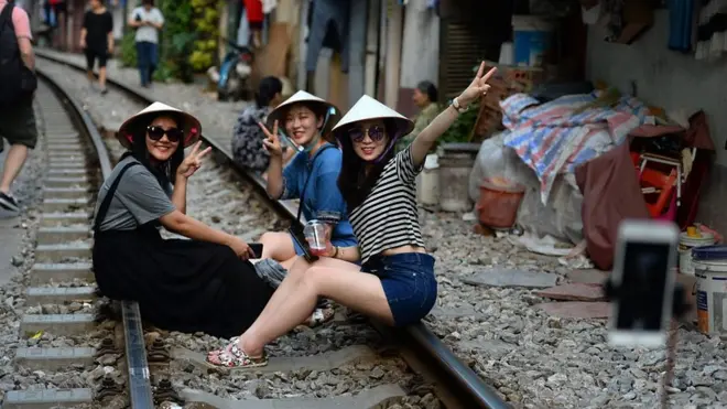Khách du lịch ngồi trên đường ray chụp hình