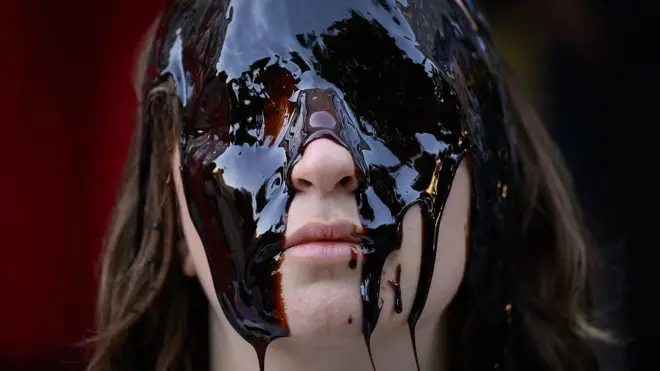 Un mujer con la cara cubierta de una sustancia pegajosa. 