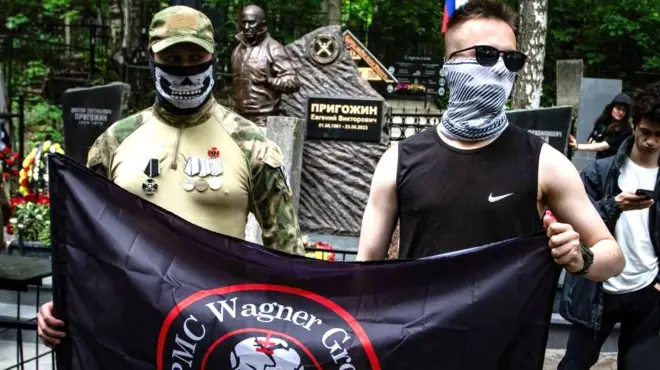 Wagner pankartı tutan yüzü maskeli iki erkek