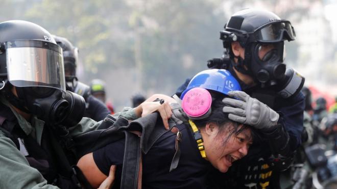 A protester is detained by riot police while attempting to leave the campus of Hong Kong Polytechnic University (PolyU) during clashes with police in Hong Kong