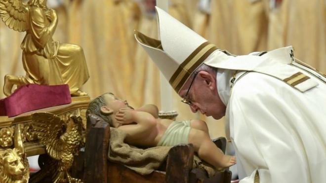 Pope Francis kisses a figurine of the baby Jesus during a Mass on Christmas Eve 2018 at St Peter's Basilica in the Vatican