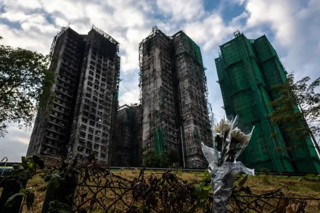 Flowers are seen in front of the Wang Fuk Court apartment blocks in the aftermath of the deadly November 26 fire in Hong Kong's Tai Po district on December 3, 2025. 