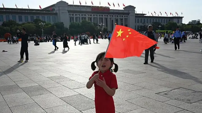 Uma criança segura a bandeira da China na Praça da Paz Celestial (Tiananmen Square), em Pequim, no Dia Nacional da China, que comemora o 76º aniversário da fundação da República Popular da China, em 1º de outubro de 2025.