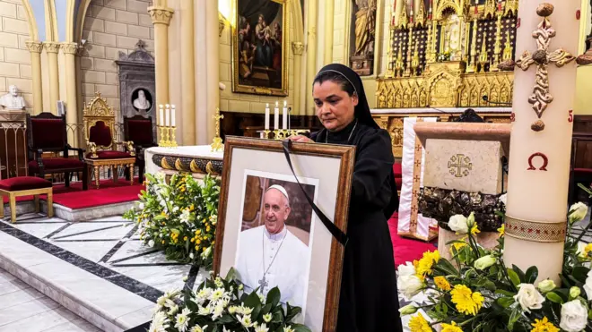 Bir rahibe Papa Francesco'nun çerçeveli resmine siyah kurdele bağlıyor