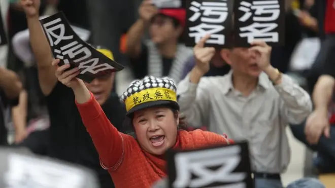 监督年金改革行动联盟动员军公教团体，18日发动“夜宿围城”行动，抗议民众举起“反污名”手牌表达诉求。