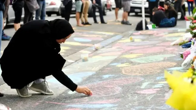 A mourner draws on the pavement outside a Mosque in Kilbirnie, Wellington
