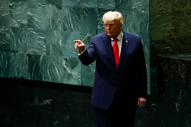 Trump em pé no palco da ONU apontado o dedo para pessoas nas cadeiras