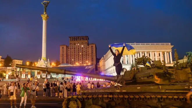 Дівчина з українським прапором стоїть на знищеному російському танку під час виставки знищеної російської військової техніки на вулиці Хрещатик у центрі Києва, Україна, 20 серпня 2022 року