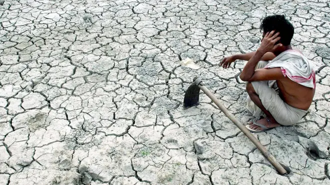 Farmer looking at parched ground in India