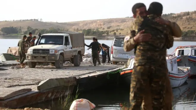 Tabka Barajı kıyısında sevinçle birbirlerine sarılan iki SDG askeri