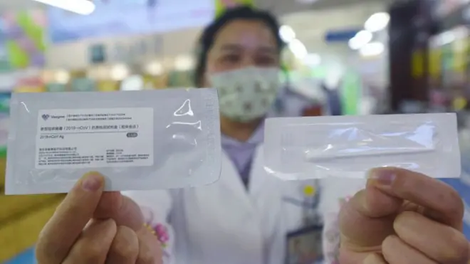 A drug store employee shows a COVID-19 antigen rapid test kit