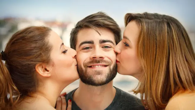 Дві дівчини цілують хлопця — стокове фото