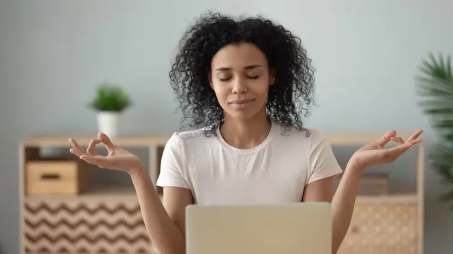 Mulher meditando enquanto trabalha no computador