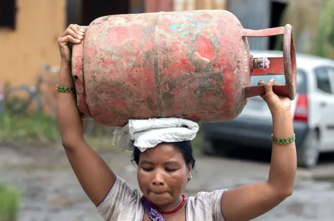 टाउकामा खाना पकाउने ग्यासको सिलिन्डर बोकेकी एक महिला