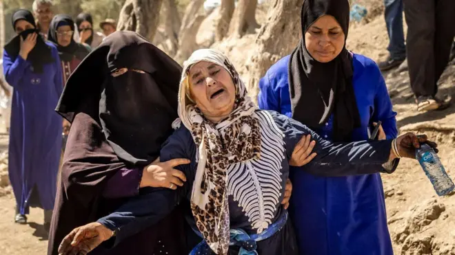 A woman is supported under her arms by two other women as she sobs following the death of relatives to the south-west of Marrakesh in 2023
