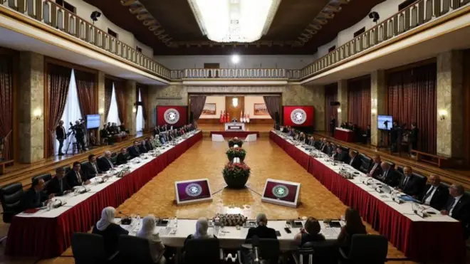 TBMM Komisyon'un toplantı görüntüsü dikdörtgen şeklinde yanyana uzun masalarda oturan takım elbiseli vekiller uzaktan görünüyor. 