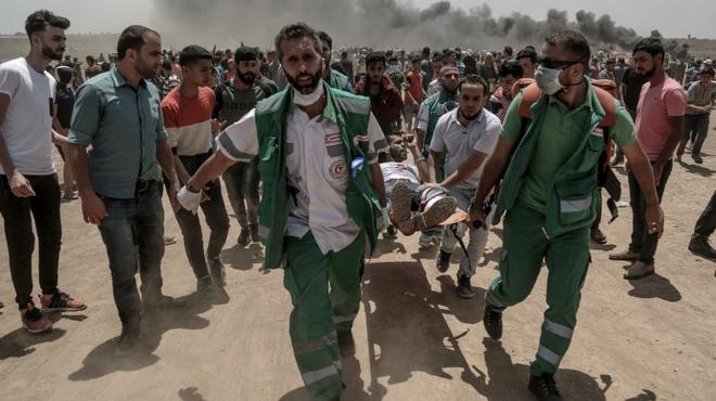 Palestinian medics carry a wounded protester near the border with Israel in the east of Jabaliya in the northern Gaza Strip, 14 May 2018