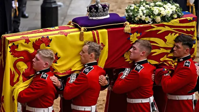 The Bearer Party from Queen's Company, 1st Battalion Grenadier Guards, carries the coffin of Queen Elizabeth II, draped in the Royal Standard with the Imperial State Crown placed on top, into Westminster Hall, London on 14 September 2022