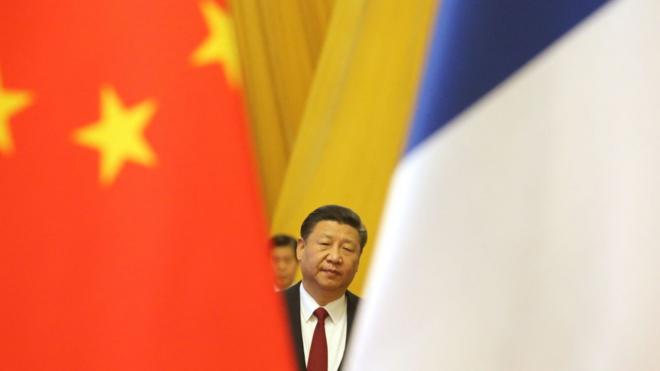 Chinese President Xi Jinping is seen between China and France's national flags in Beijing on January 9, 2018. - Chinese President Xi Jinping and French counterpart Emmanuel Macron met Tuesday for talks and to oversee the signing of business deals as the two global leaders seek closer ties