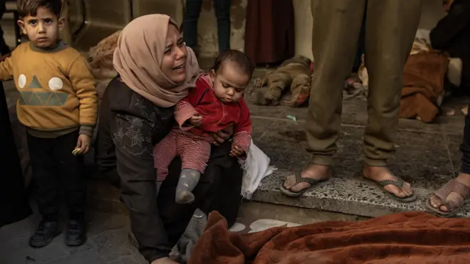 امرأة مع طفليها تبكي بعد مقتل أحد أفراد عائلتها في قصف إسرائيلي.