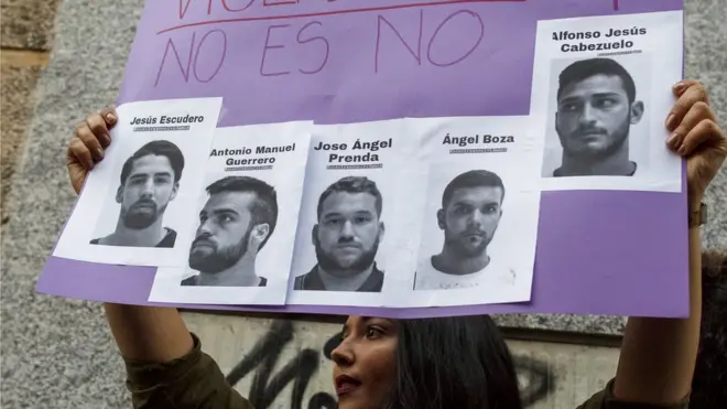 A woman holds aloft a poster during a demonstration - on it are the photographs of the "wolf pack" with the Spanish words for "no is no"