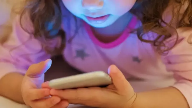 طفلة تطالع شاشة هاتف محمول