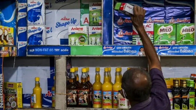 A shopkeeper pulls put a package of non-fat milk at a store in Colombo August 19, 2021. - With the country of 21 million already facing shortages of imported cooking gas and sugar because of the lack of dollars, the Central Bank of Sri Lanka increased its deposit and lending rates by 50 basis points to 5.0 percent and 6.0 percent respectively.