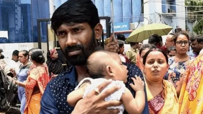 बच्चे को कोद में लिए खड़ा एक शख्स