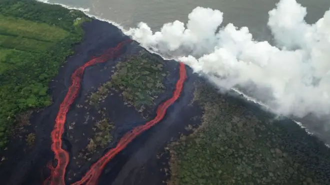 Des panaches de vapeur s'élèvent alors que la lave pénètre dans l'océan Pacifique, après s'être écoulée vers l'eau depuis une fissure du volcan Kilauea, sur la Grande île d'Hawaï, le 21 mai 2018 près de Pahoa, à Hawaï.