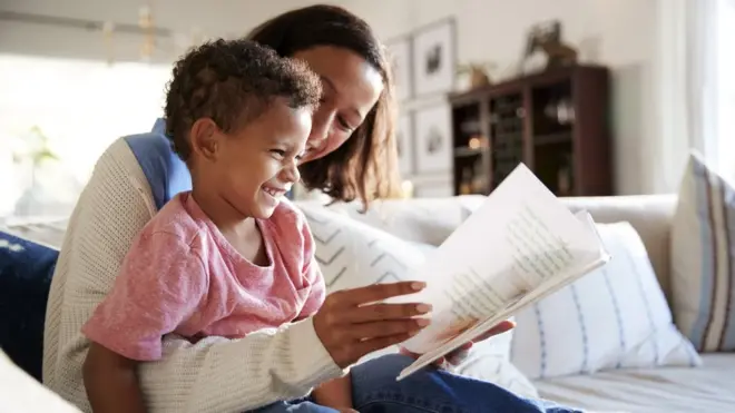 Mãe lendo livro com garoto no colo