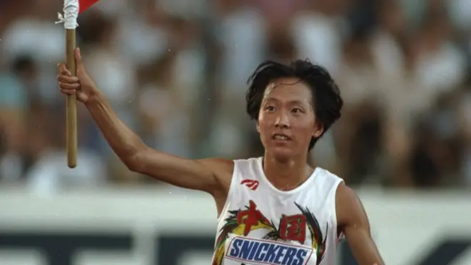 Junxia Wang of China carries two Chinese flags on a lap of honour after winning the 10 000 metres event at the World Championships in Stuttgart, Germany