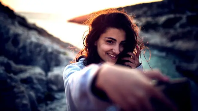 Mujer tomándose un selfie al atardecer.