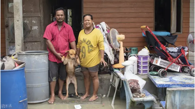 อนงค์พร สุวรรณสังข์ (ขวา) และ วีระศักดิ์ สุวรรณวงศ์ (ซ้าย) ยืนหน้าบ้านที่เสียหายหนัก ใน ต.แหลมตะลุมพุก อ.ปากพนัง จ.นครศรีธรรมราช